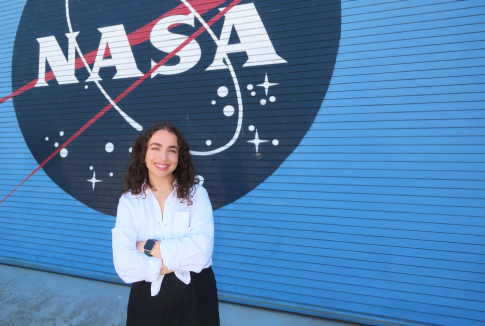 Josephine Maglio framför en NASA skylt mot blå bakgrund
