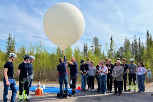 EXPLORA-1024x683.png Ett gäng människor som håller i en stor ballong.