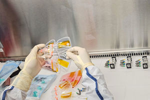 Crew 12 experiment.jpg Händer som håller i experiment i ett renrum.