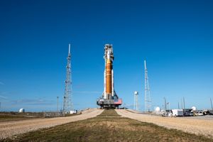 KSC-01172026-Artemis II_Rollout-24~large.jpg En raket på marken mot en blå himmel