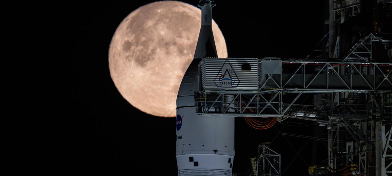 Artemis II at the pad Full Snow Moon 02012026_4~large.jpg Månen sedd på himlen bakom raketen Space Launch System där den står på uppskjutningsrampen.