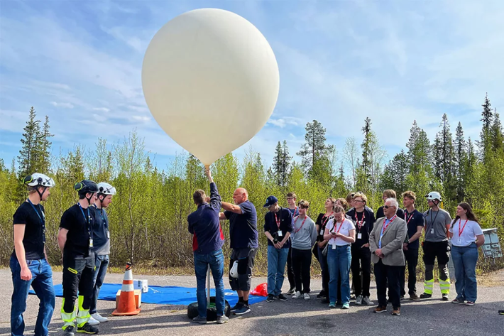 Ett gäng människor som håller i en stor ballong.