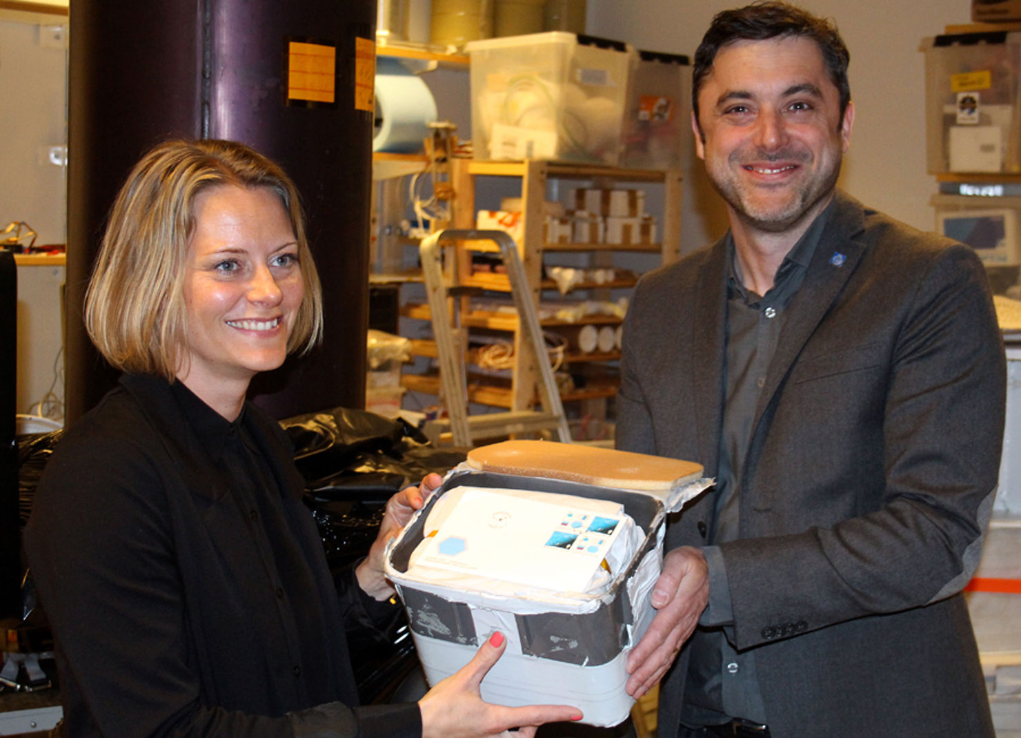 Maria Blomberg, på PostNord Frimärken, tar emot de 249 rymdbreven från projektledaren för PoGOLite professor Mark Pearce.