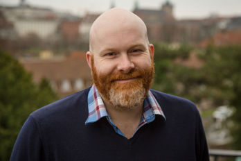 Per Bjerkeli.jpg En flintskallig man med rödhårigt skägg.