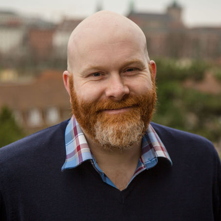 Per Bjerkeli.jpg En flintskallig man med rödhårigt skägg.