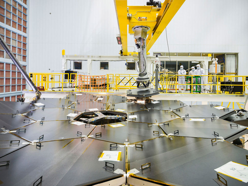 Speglarna på rymdteleskopet James Webb sätts på plats med hjälp av en robotarm.