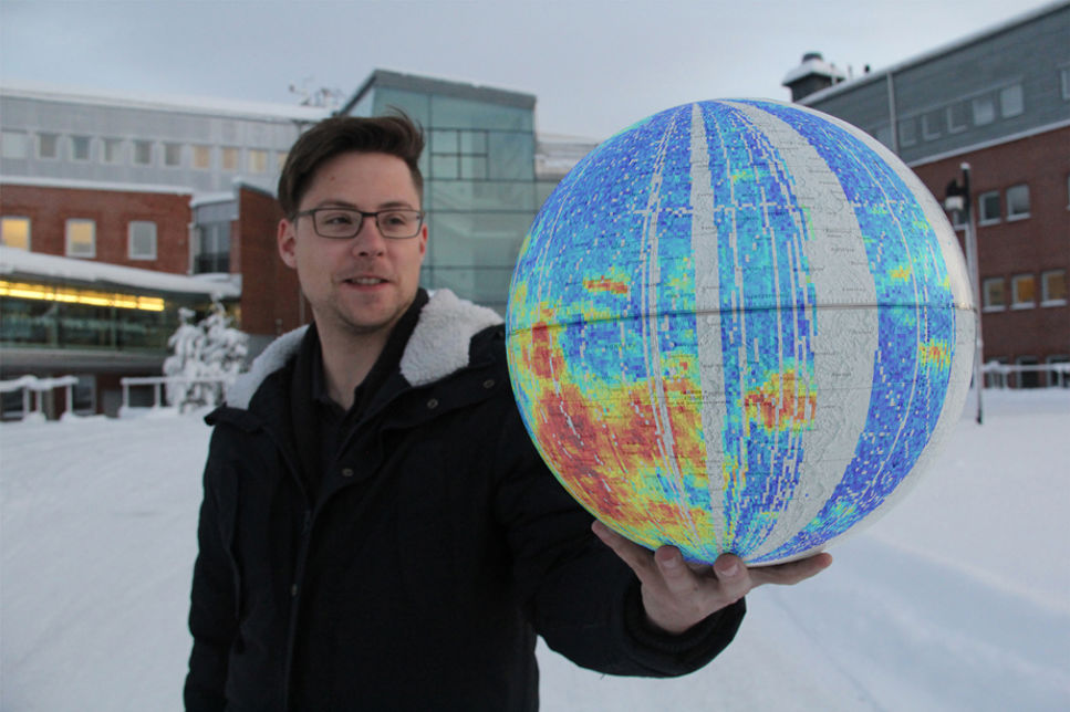 Charles Lue håller upp en månglob som visar reflektion av solvinden från magnetiska fält på månens yta. 
