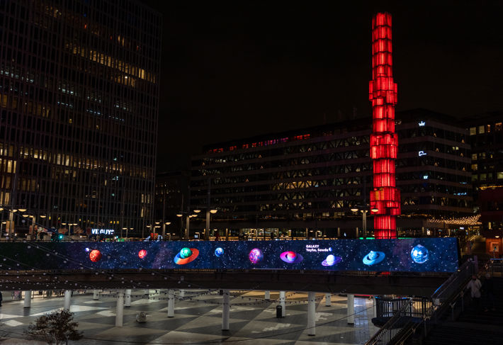 Sergels torg på kvällen med planeter på en led-skärm under.