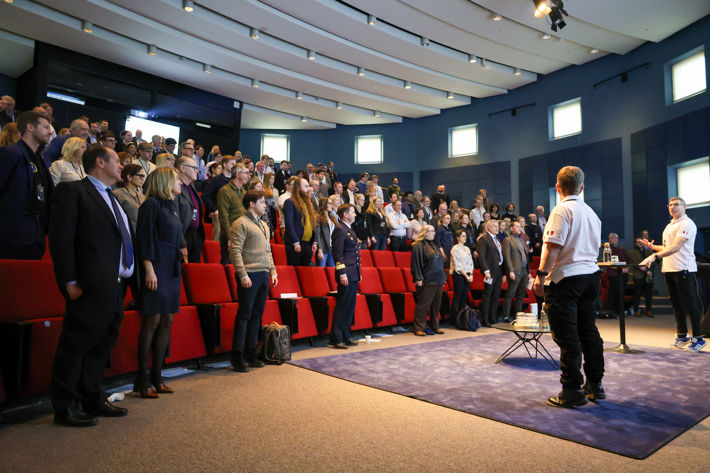 En publik som ställer sig upp i en övning.