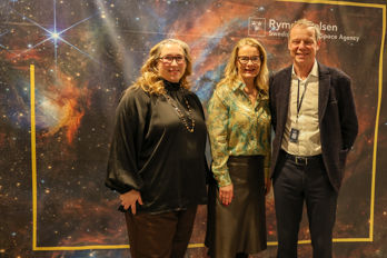 Ella Lotta och Christer.jpg Tre glada personer framför en bild på en nebulosa.