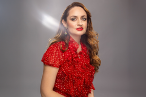 Beatriz Villaroell.png En kvinna i röd klänning mot grå bakgrund