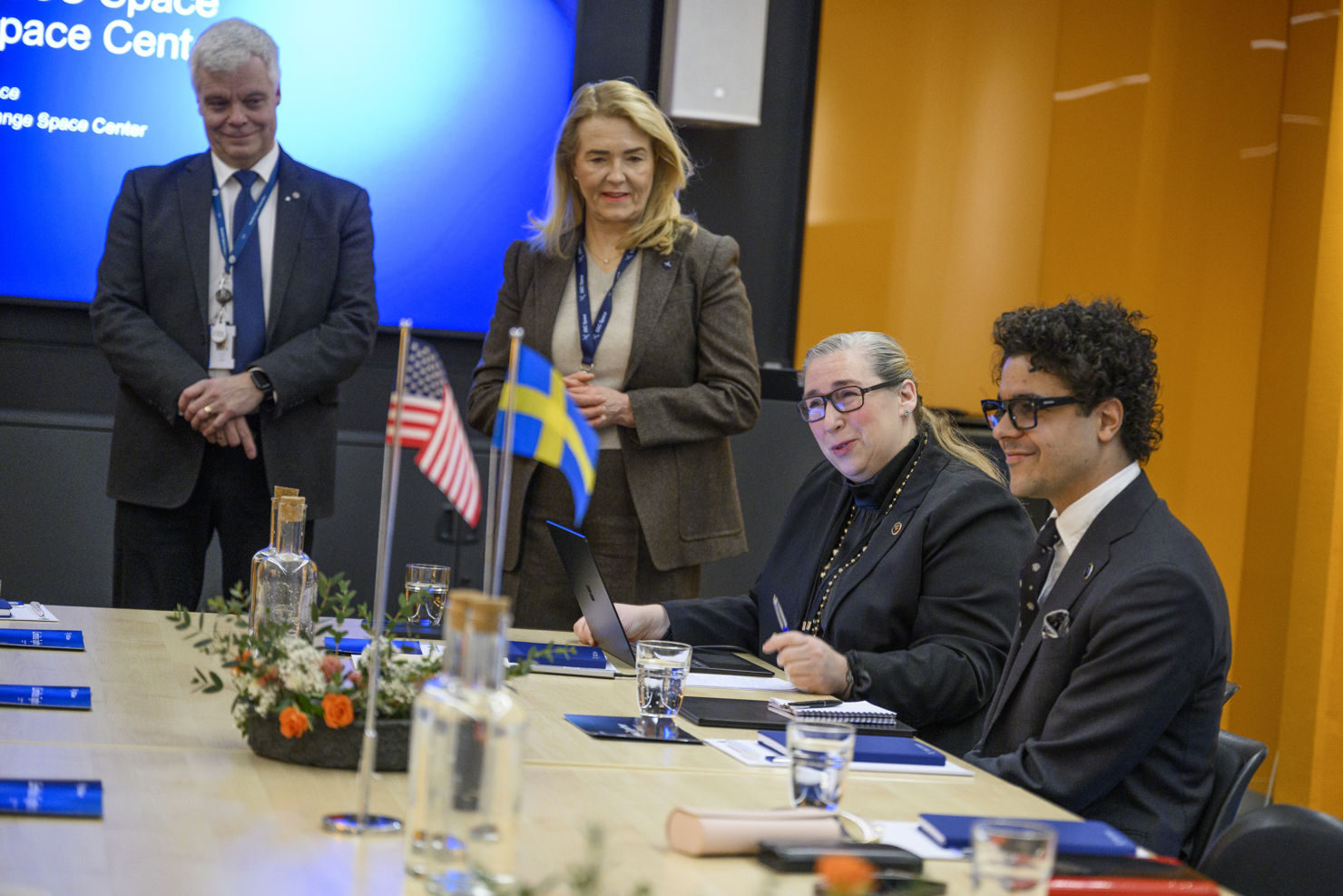 Fyra personer vid ett konferensbord med den svenska och amerikanska flaggan.