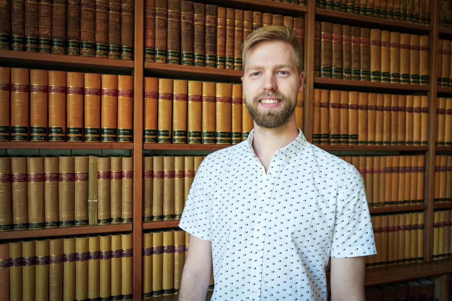 Måns Holmberg framför en bokhylla