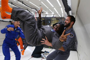Astronauten Claudie Haigneré från Frankrike, till vänster i bild, visar en tjej hur man rör sig i tyngdlöshet.