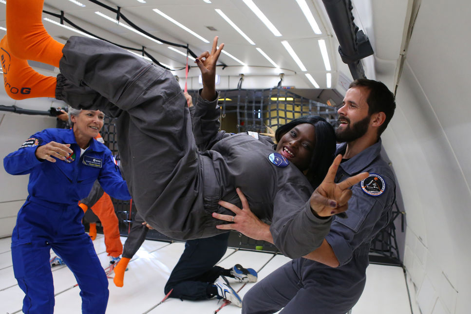 Astronauten Claudie Haigneré från Frankrike, till vänster i bild, visar en tjej hur man rör sig i tyngdlöshet.