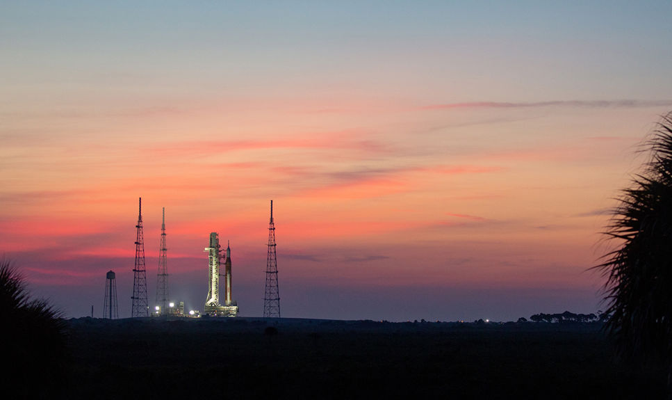 Rymdraketen SLS står på startplattan i solnedgången.