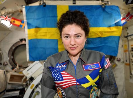 Jessica Meir ombord på den internationella rymdstationen ISS. På sin overall har hon Svenska flaggan och USA:s flagga. I bakgrunden syns en stor svensk flagga.