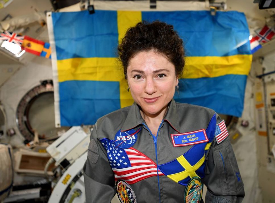 Jessica Meir ombord på den internationella rymdstationen ISS. På sin overall har hon Svenska flaggan och USA:s flagga. I bakgrunden syns en stor svensk flagga.