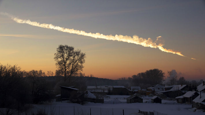 Bilden visar ett spår av ånga på en orange-färgad himmel över det snöiga landskapet i Ryssland.