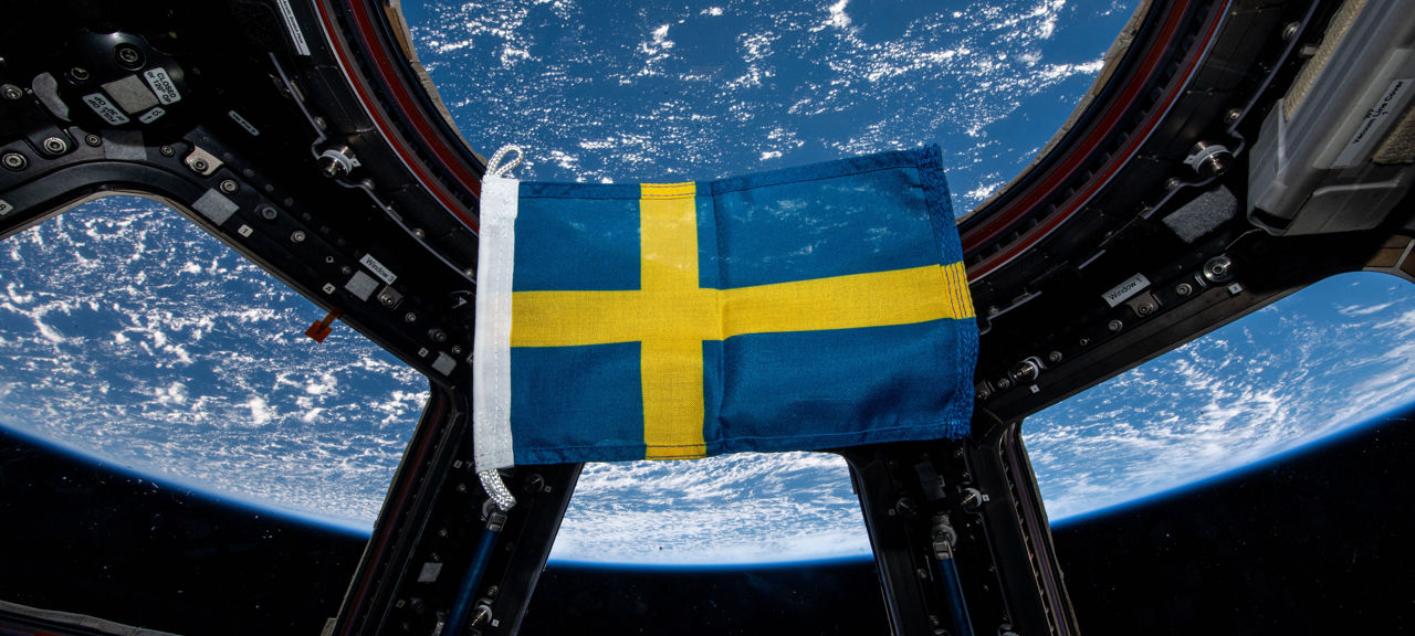 Svensk flagga rymden.jpg En svensk flagga som svävar i tyngdlöshet på den internationella rymdstationen.